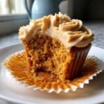Close-up of a Pumpkin Cupcakes With Maple Frosting, showing the moist interior and thick swirl of frosting.