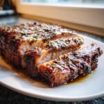 Close-up of a perfectly cooked Pork Roast, sliced to show juicy interior and herb crust.