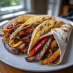 Three delicious Portobello Mushroom Fajitas filled with grilled mushrooms and colorful peppers on a white plate.