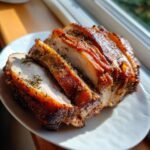 Close-up of sliced Porchetta roast showing juicy interior and crispy, herb-seasoned crackling skin.