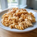 A serving of Slow Cooker Creamy Chicken Pasta featuring rotini noodles coated in a rich, orange-tinted cream sauce with shredded chicken.