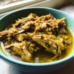 Close-up of tender, shredded pork loin submerged in vibrant green sauce, representing Slow Cooker Pork Loin Chile Verde.
