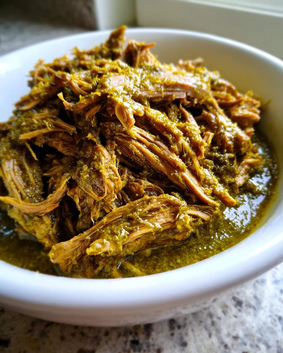 Close-up of tender, shredded pork loin coated in vibrant green sauce from Slow Cooker Pork Loin Chile Verde.