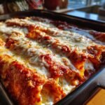 Close-up of baked Manicotti Recipe tubes covered in rich tomato sauce and bubbly, melted mozzarella cheese.