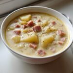 Close-up of a creamy bowl of Ham And Potato Soup with chunks of ham and potatoes, topped with pepper.
