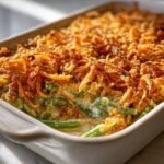 A close-up of a creamy green bean casserole topped with crispy fried onions, perfect for Thanksgiving Casseroles.