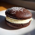 A single, rich chocolate Old Fashioned Whoopie Pie filled with thick white cream and dusted with powdered sugar.