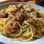 Close-up of spaghetti tossed in garlic butter sauce, topped with seasoned shrimp and grated Parmesan for Olive Garden Chicken Scampi.