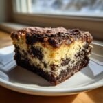 A close-up of a square slice of marbled Oreo Dump Cake showing light and dark chocolate layers on a white plate.