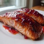 Two salmon fillets glazed with a shiny, dark red sauce, likely made from leftover cranberry sauce recipes.