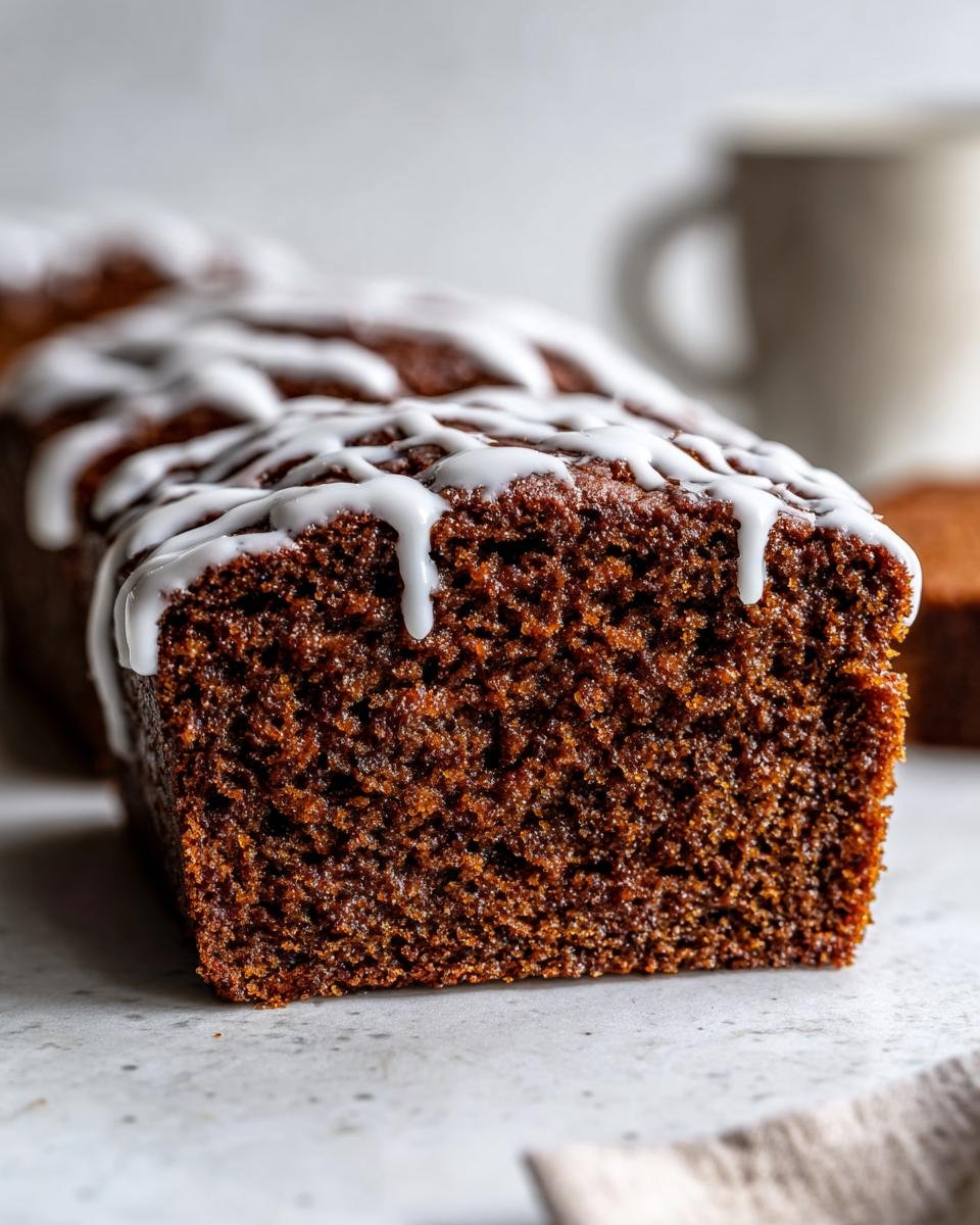 Cross-section of a rich, moist Starbucks Gingerbread Loaf topped with white vanilla icing drizzle.