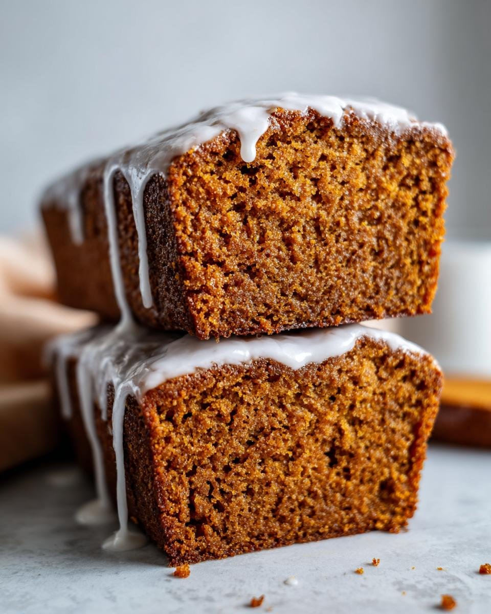 Two stacked slices of moist Starbucks Gingerbread Loaf, drizzled heavily with white vanilla icing.