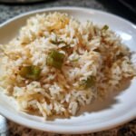 Close-up of a white bowl filled with fluffy Texas Roadhouse Seasoned Rice mixed with browned onions and green onion pieces.