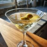 Close-up of a chilled Vodka Cocktails Martini in a coupe glass, garnished with two pimento-stuffed green olives.