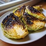 Four wedges of perfectly charred cabbage showing deep brown, caramelized edges resting on a white serving plate.