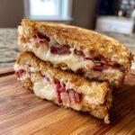 Close-up of a Bacon Grilled Cheese Sandwich cut in half, showing gooey melted cheese and crispy bacon inside.