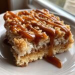 A decadent square of Caramel Coconut Bars topped with a thick, glossy caramel drizzle.