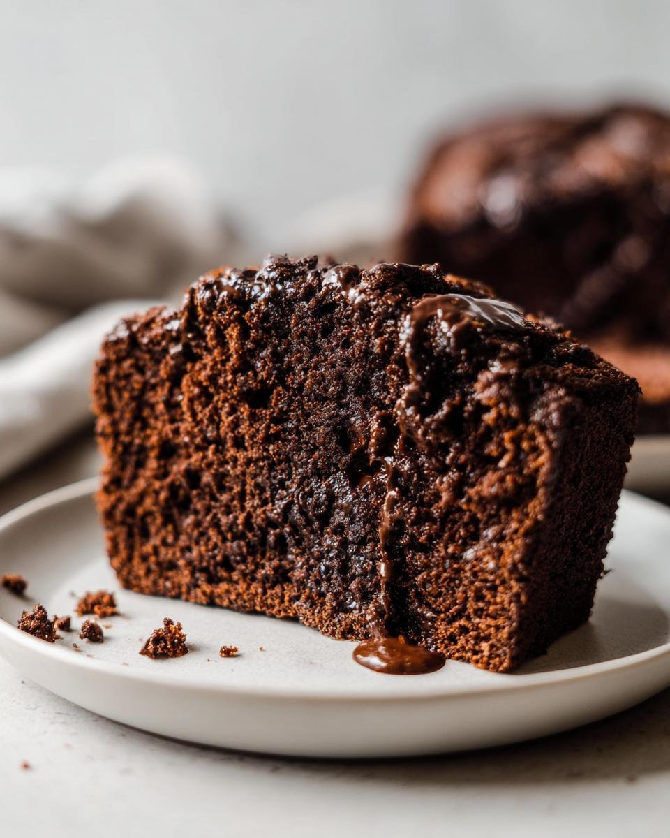 Close-up of a rich, moist slice of Double Chocolate Banana Bread drizzled with chocolate glaze.