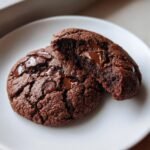 Close-up of a rich, dark Double Chocolate Chip Cookie, broken open to show melted chocolate chips.