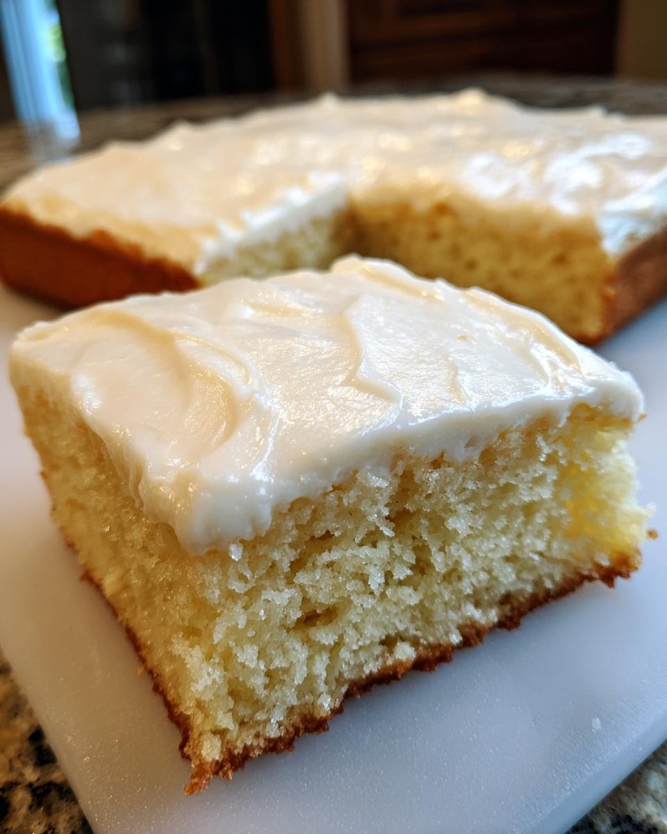 A close-up of a square slice of Frosted Sugar Cookie Bars showing the thick, soft texture and creamy white frosting.