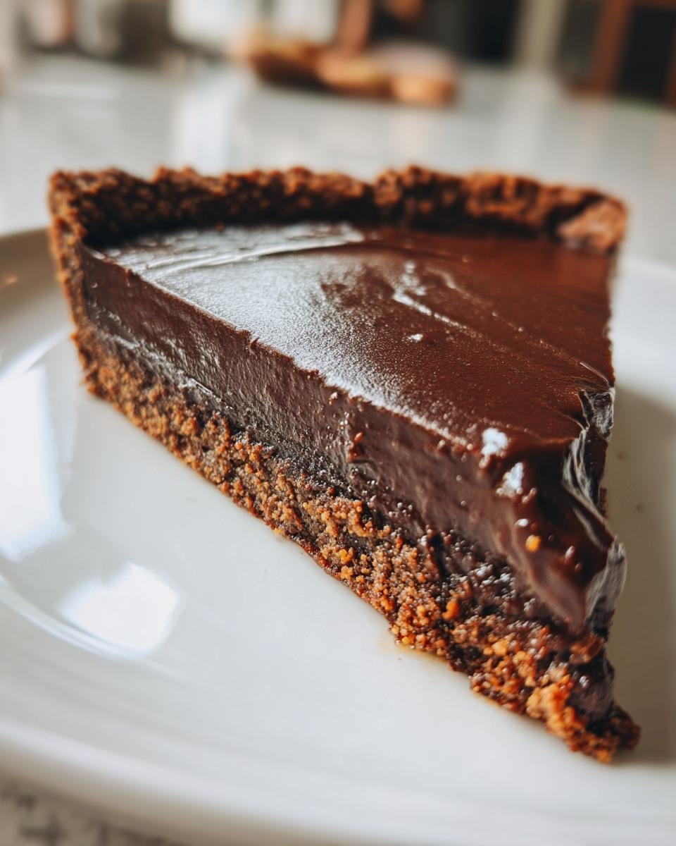 Close-up of a decadent slice of Fudge Dessert Pizza showing the thick, glossy chocolate filling and crumbly crust.