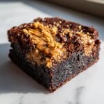 Close-up of a rich, fudgy Biscoff Brownies square topped with melted cookie butter and crumbs.