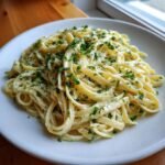 A close-up of creamy Lemon Ricotta Pasta tossed with fettuccine and topped generously with chopped fresh parsley.
