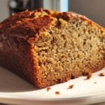 Close-up of a thick slice of Moist Banana Cake, highlighting its dense, moist crumb and dark golden crust.
