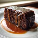 A rich, dark slice of Sticky Toffee Pudding generously covered in dripping toffee sauce.