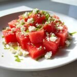 Bright red cubes of watermelon topped with crumbled feta cheese and fresh mint, served as a Watermelon Feta Salad.