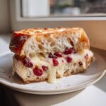 Close-up of a grilled Brie Cranberry Sourdough Bread slice with melted brie oozing out over dried cranberries.