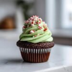 A single Chocolate Peppermint Cupcake featuring a rich chocolate base, bright green mint frosting, and crushed candy canes on top.