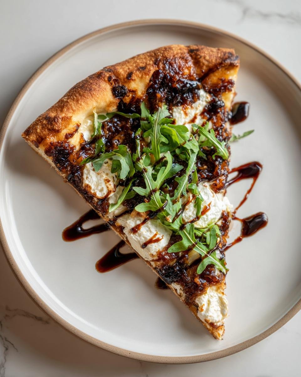A single slice of Fig Jam Goat Cheese Pizza topped with creamy goat cheese, dark fig jam, and fresh arugula.