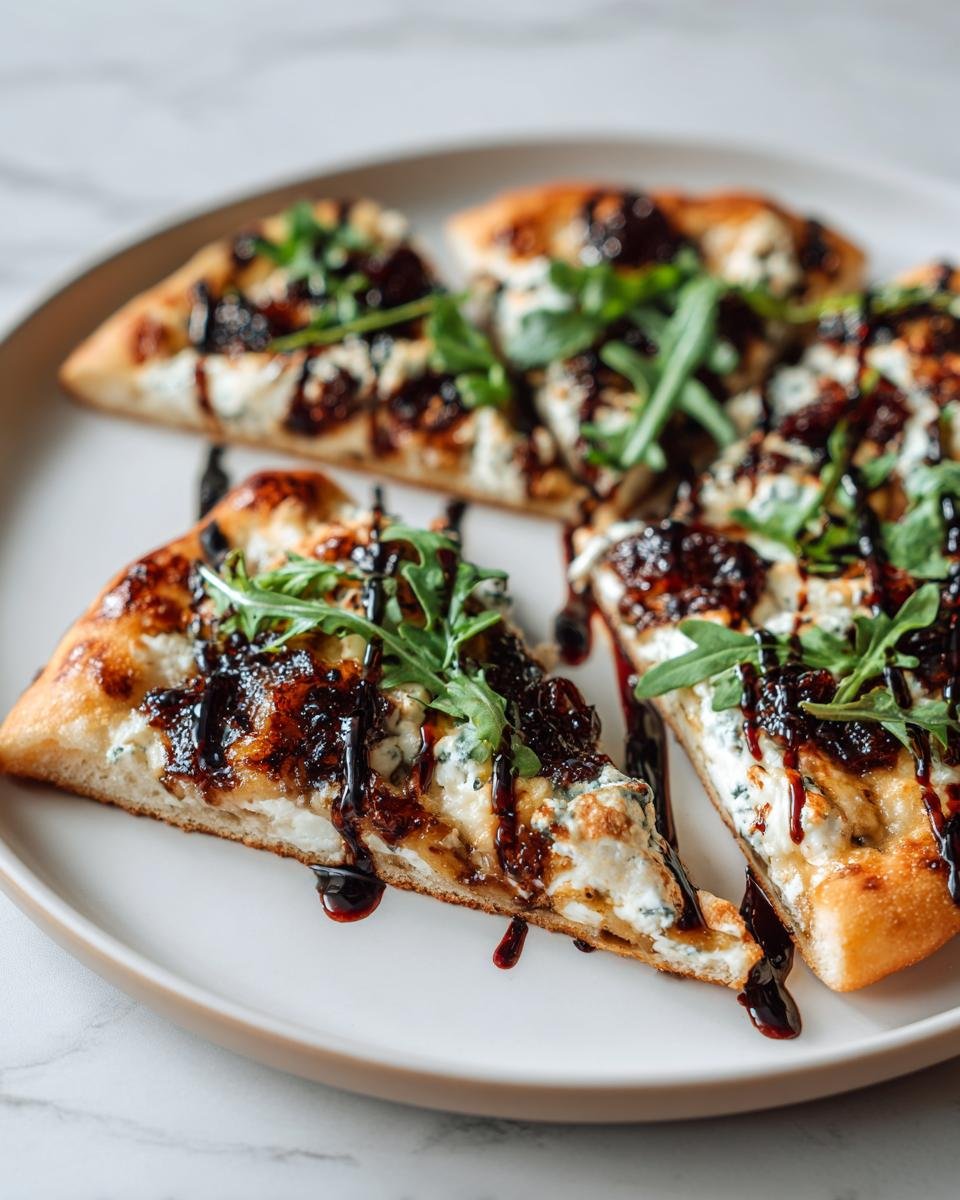 Close-up of Fig Jam Goat Cheese Pizza slices topped with arugula and balsamic glaze.