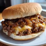 Close-up of a delicious French Onion Sloppy Joes sandwich overflowing with meat, caramelized onions, and melted cheese.