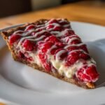 A close-up slice of Pizza Hut Cherry Dessert Pizza topped with bright red fruit filling and white icing drizzle.