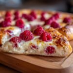 Close-up of a slice of Raspberry Brie Dessert Pizza showing melted cheese and fresh raspberries on a thick crust.