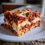 A generous, layered slice of Vampire Lasagna featuring rich meat sauce and creamy ricotta cheese, topped with melted mozzarella.
