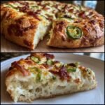 A thick-crust Jalapeno Popper Pizza topped with cream cheese, melted cheese, bacon, and sliced jalapenos.