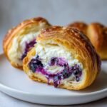 Close-up of a Blueberry Cheesecake Crescent cut in half, showing creamy filling and blueberry swirl.