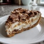 A thick slice of no-bake Butterfinger Pie with creamy filling and topped with chopped Butterfinger candy pieces.