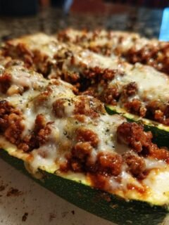 Two freshly baked Stuffed Zucchini Boats filled with meat sauce and melted mozzarella cheese.
