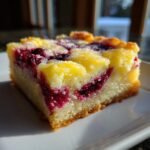 A single, thick square slice of Cranberry Lemon Bars with a bright yellow top and visible swirls of deep red cranberry filling.