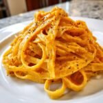 Close-up of creamy Pumpkin Alfredo Pasta tossed with fettuccine and sprinkled with black pepper.