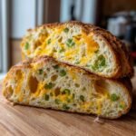 Close-up of Jalapeno Cheddar Bread cut in half, showing melted cheddar cheese pockets and green jalapeno pieces throughout the airy crumb.