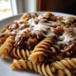 Close-up of creamy French Onion Pasta featuring rotini noodles coated in rich sauce and topped with melted white cheese.