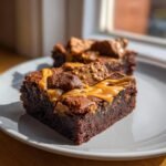 Close-up of a rich, fudgy Biscoff Brownies square topped with caramel sauce and chunks of Biscoff spread.