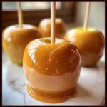A close-up of a perfectly coated caramel apple, dripping slightly, ready for enjoying one of these Caramel Apple Creations.
