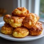A stack of fluffy, golden-brown Pancake Bites piled high on a white plate, ready to eat.