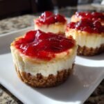 A close-up of delicious Mini Cherry Cheesecakes with a thick graham cracker crust and bright red cherry topping.